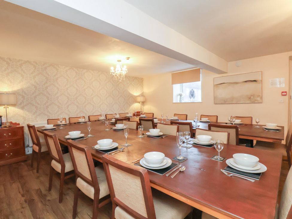A dining room with a large table set for meals at Honeysuckle in Filey