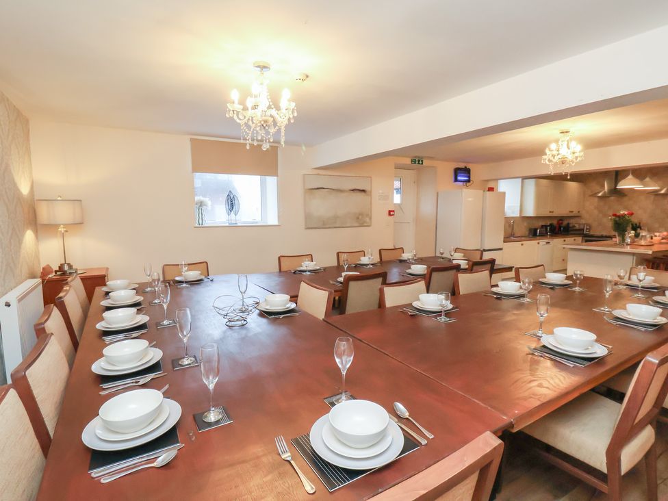 A dining room with a large table set for a meal at Honeysuckle in Filey