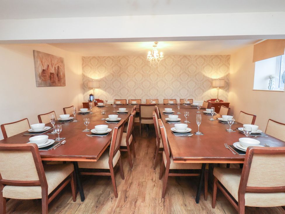 A dining room with a large table set for meals at Honeysuckle in Filey