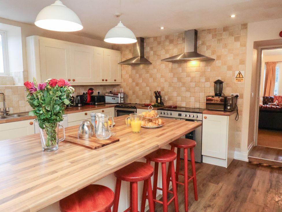 A kitchen with stools and flowers on the countertop at Honeysuckle in Filey