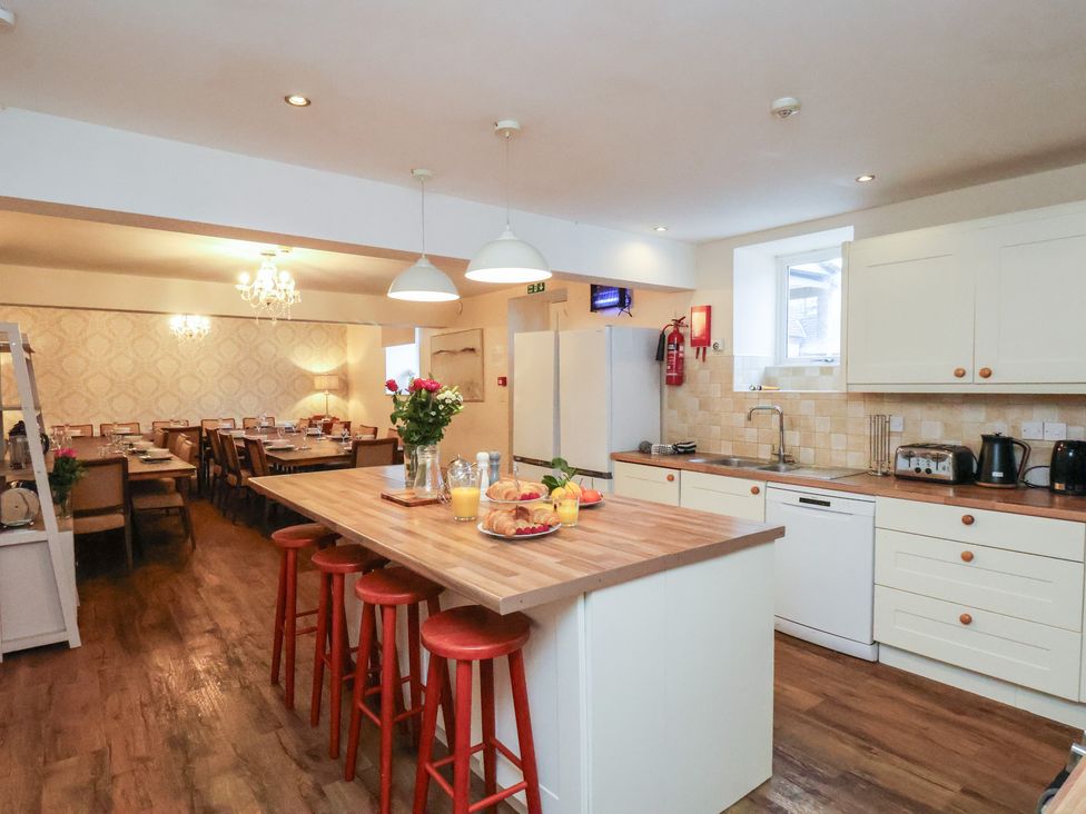 A kitchen with a table and stools at Honeysuckle in Filey