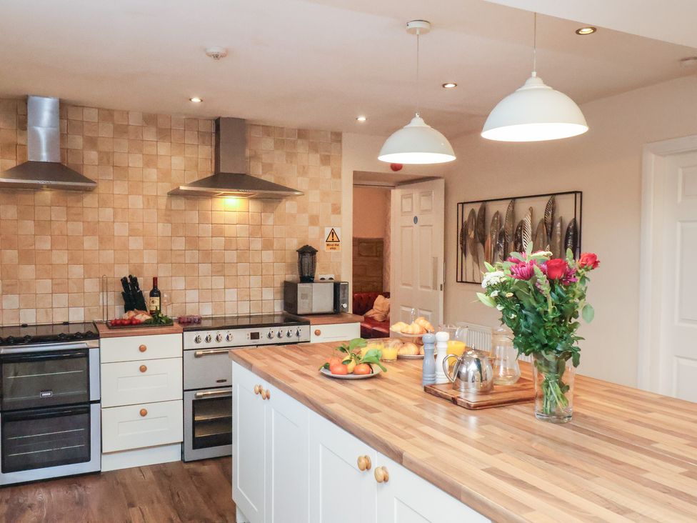 A kitchen with a stove and kitchen island at Honeysuckle in Filey