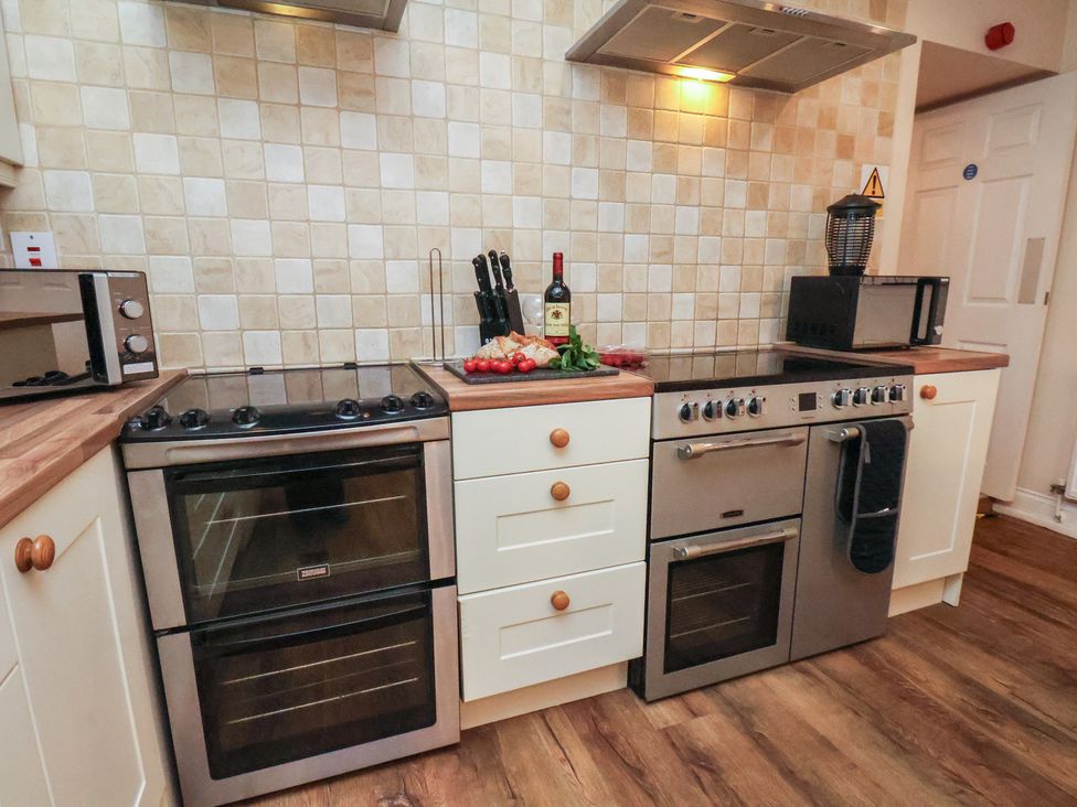 A kitchen with a stove, oven, and microwave at Honeysuckle in Filey