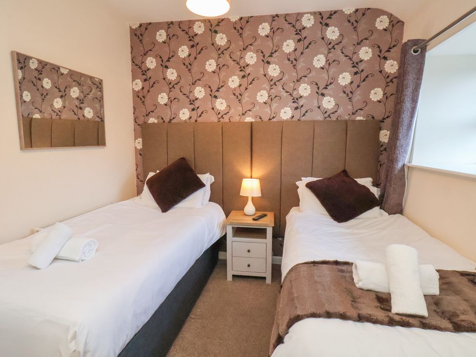 A bedroom with two single beds and a lamp at Honeysuckle in Filey