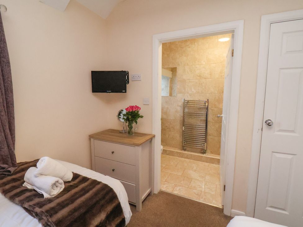 A bedroom with a bed and door to the bathroom at Honeysuckle in Filey