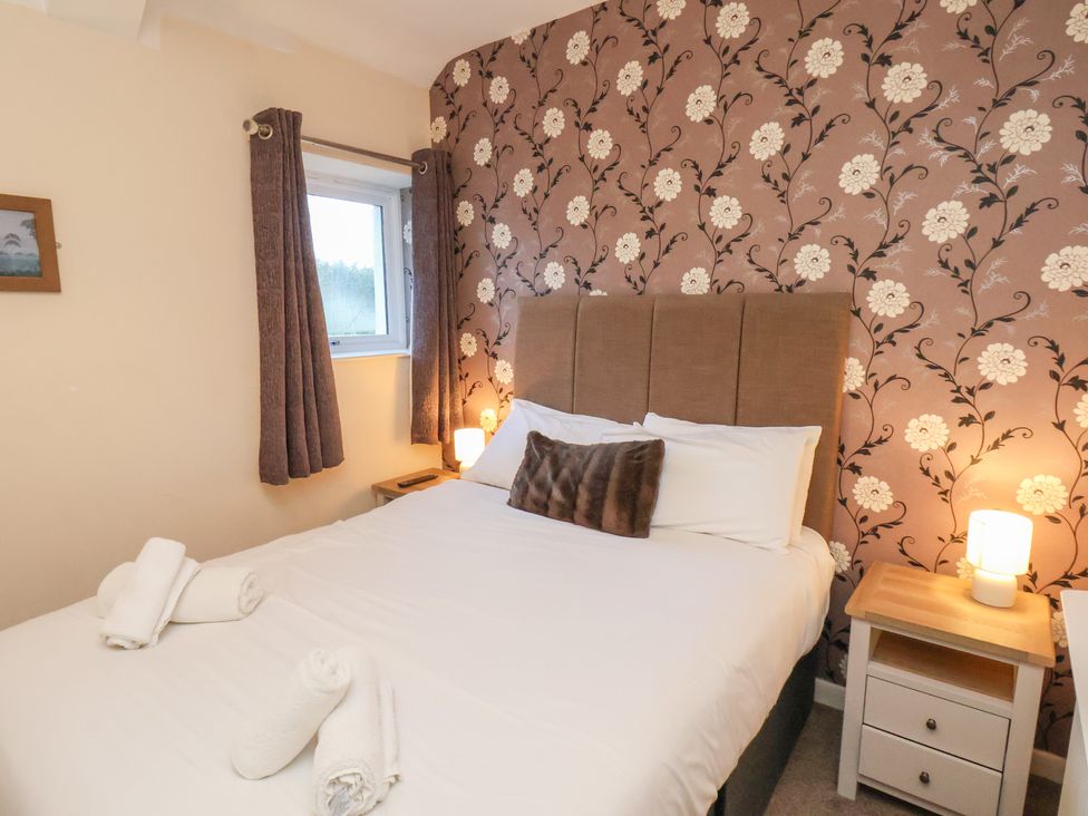 A bedroom with a bed and bedside table at Honeysuckle in Filey