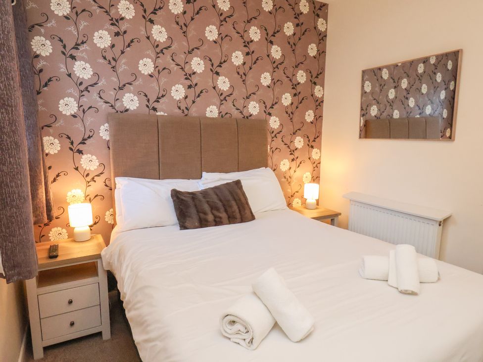 A bedroom with a bed and nightstand at Honeysuckle in Filey