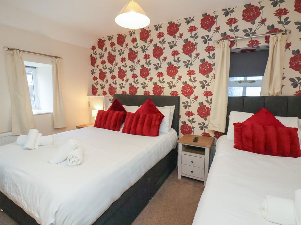 A bedroom with two beds and a floral wallpaper at Honeysuckle in Filey