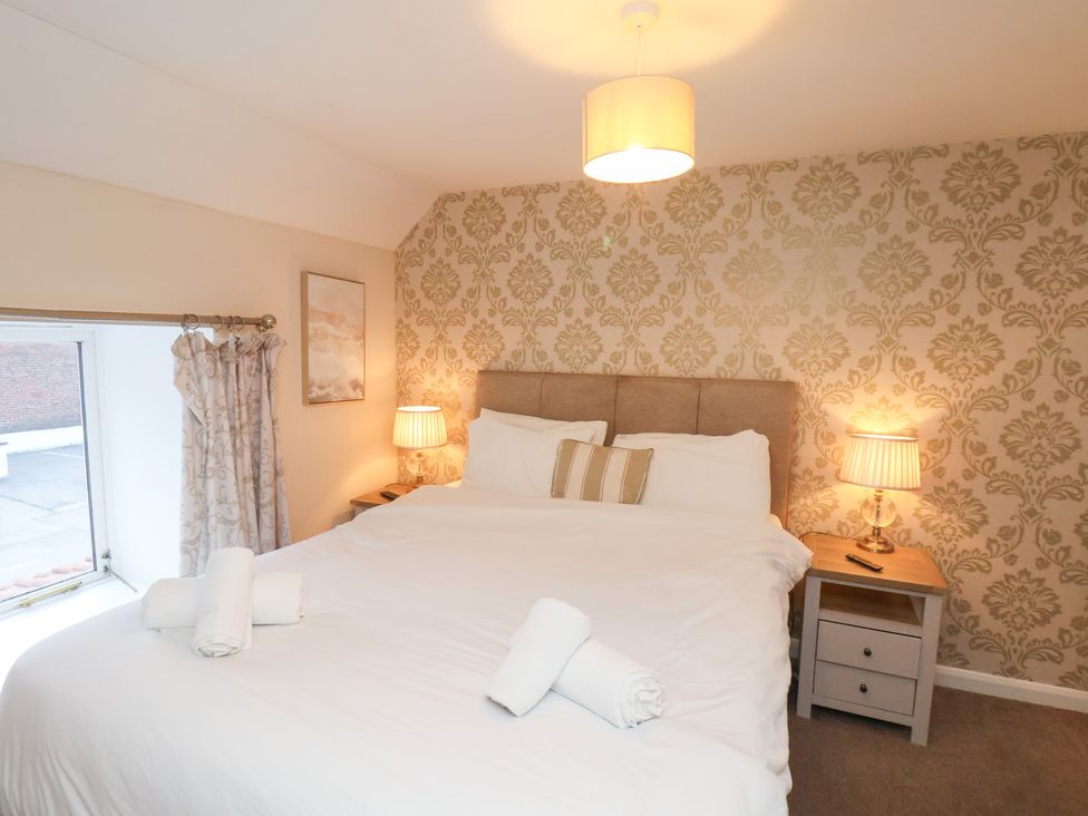 A bedroom with a bed and bedside lamps at Honeysuckle in Filey