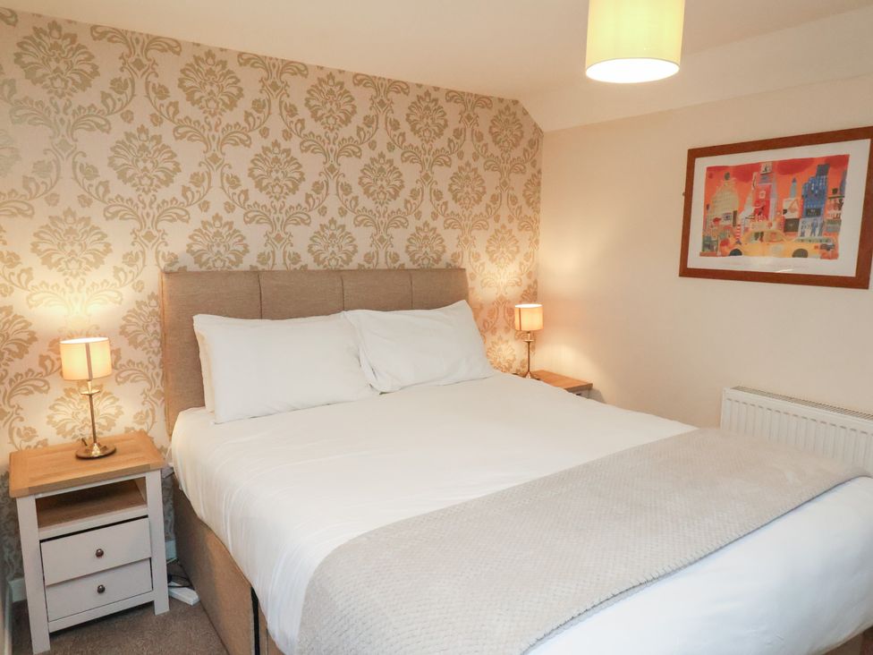 A bedroom with a bed and nightstands at Honeysuckle in Filey