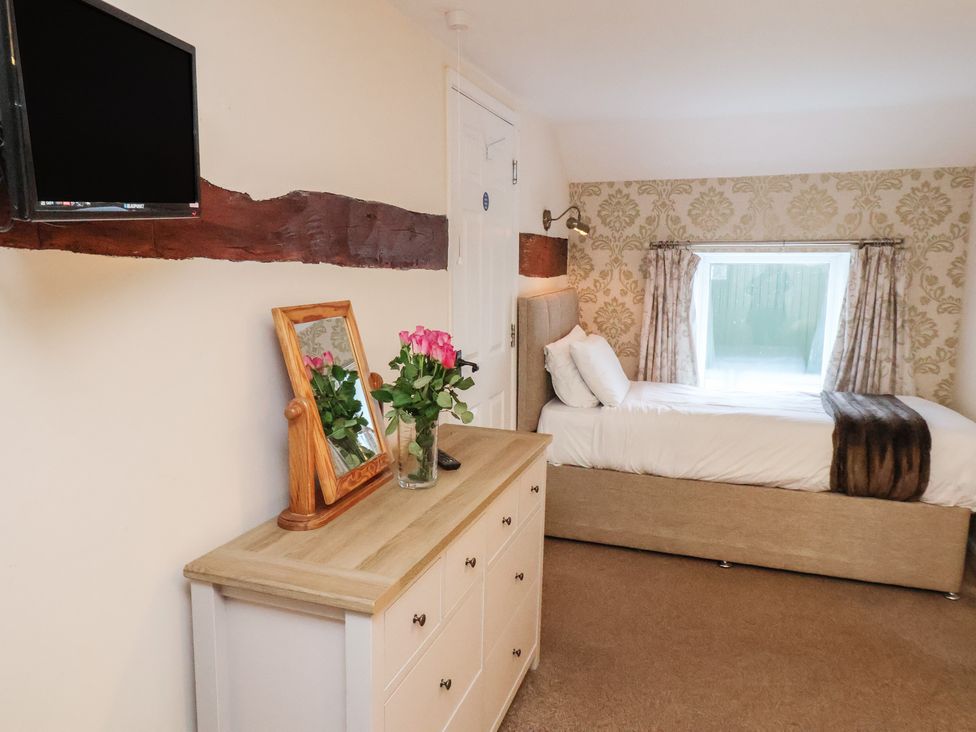 A bedroom with a bed, television, and dresser at Honeysuckle in Filey