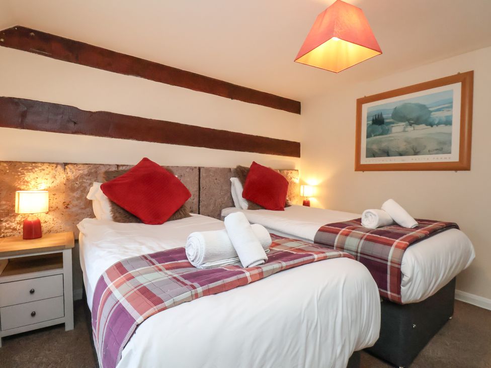 A bedroom with two beds and a lamp at Honeysuckle in Filey