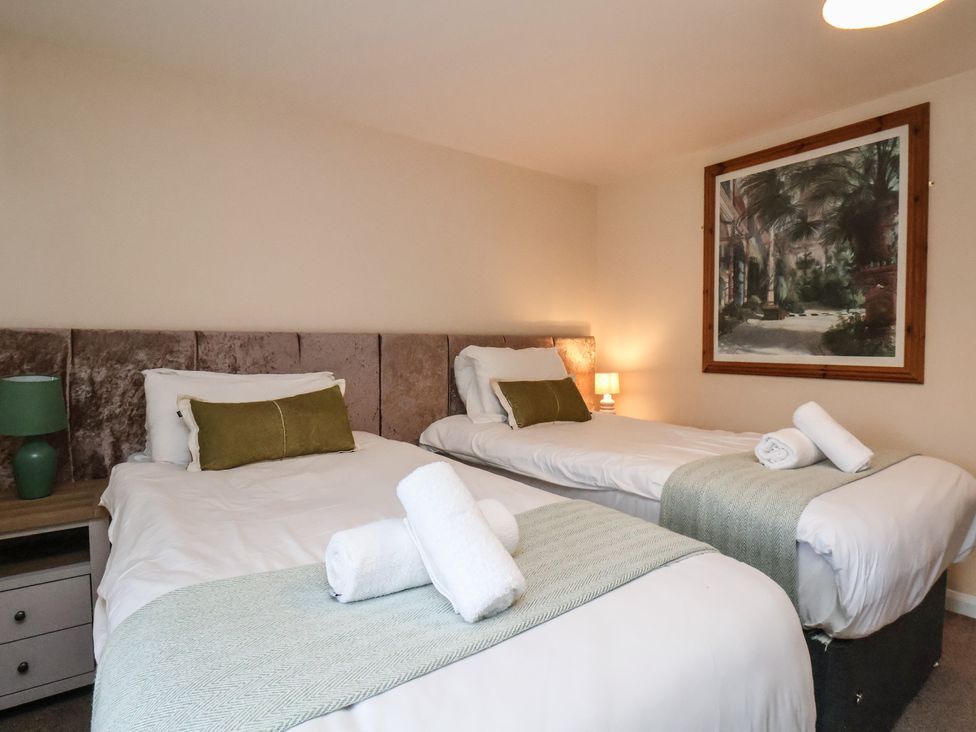 A bedroom with two beds and a painting at Honeysuckle in Filey