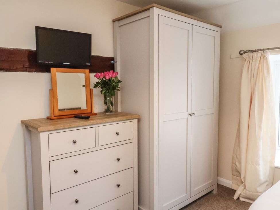 A bedroom with furniture including a television and a wardrobe at Honeysuckle in Filey