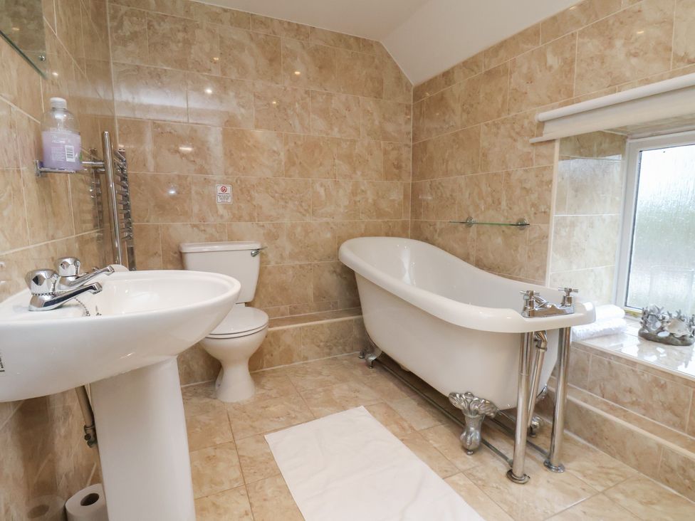 A bathroom with a bathtub, toilet, and sink at Honeysuckle in Filey