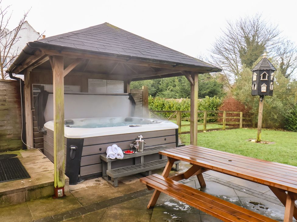 A garden with a hot tub and table at Honeysuckle in Filey