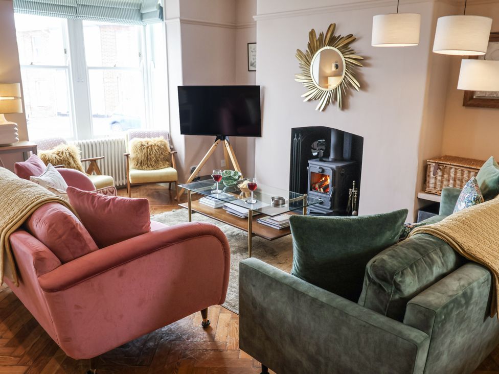 A living room with a television and a fireplace at Astondene, East Cliff in Southwold
