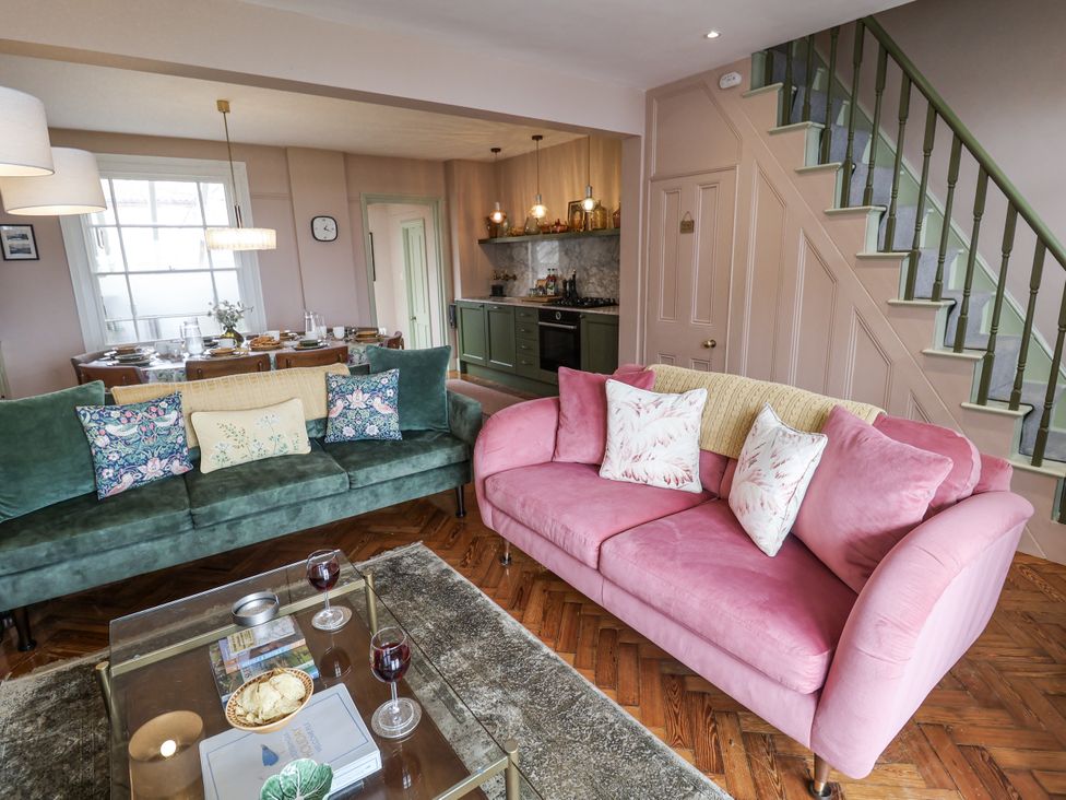 A living room with a green sofa and pink sofa at Astondene, East Cliff in Southwold