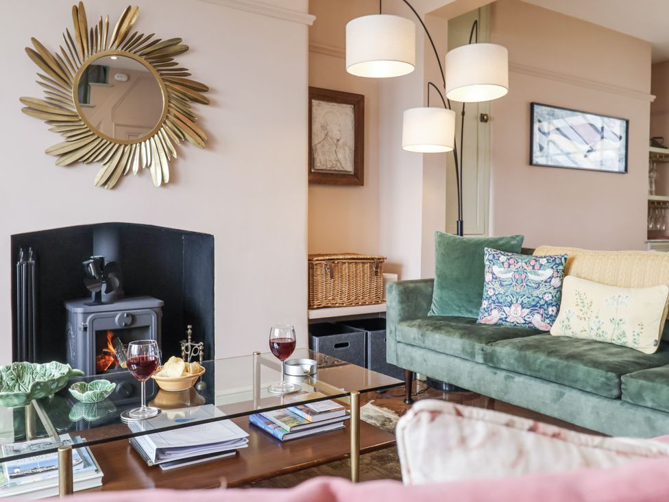 A living room with a green sofa and a coffee table at Astondene, East Cliff Southwold