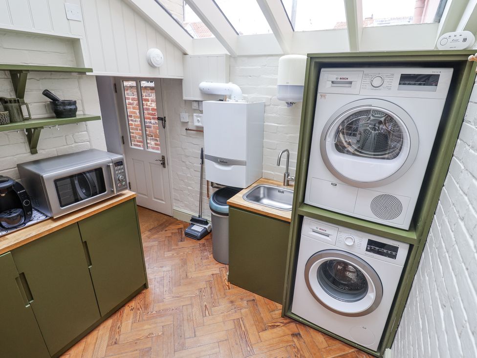 A utility room with washing machine and dryer at Astondene, East Cliff, Southwold