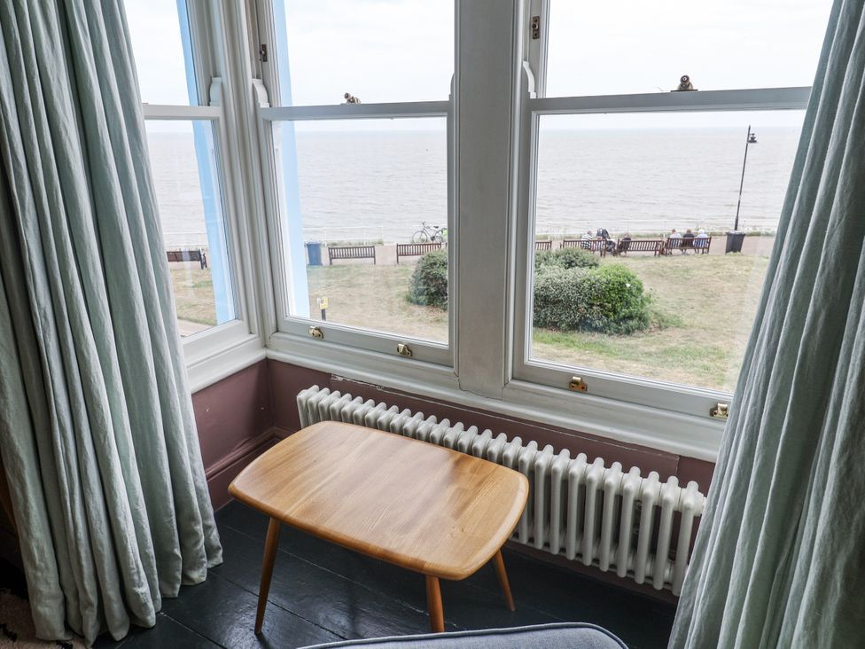 A living room with a table and view of the sea at Astondene, East Cliff Southwold