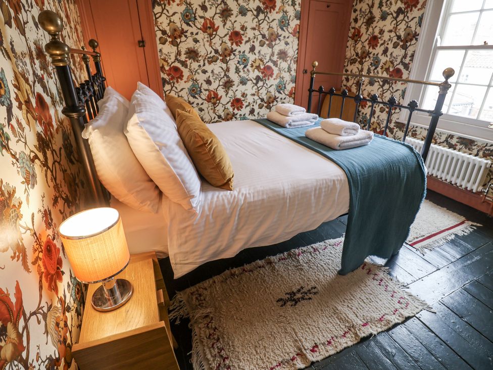 A bedroom with a bed and decorative wallpaper at Astondene, East Cliff Southwold
