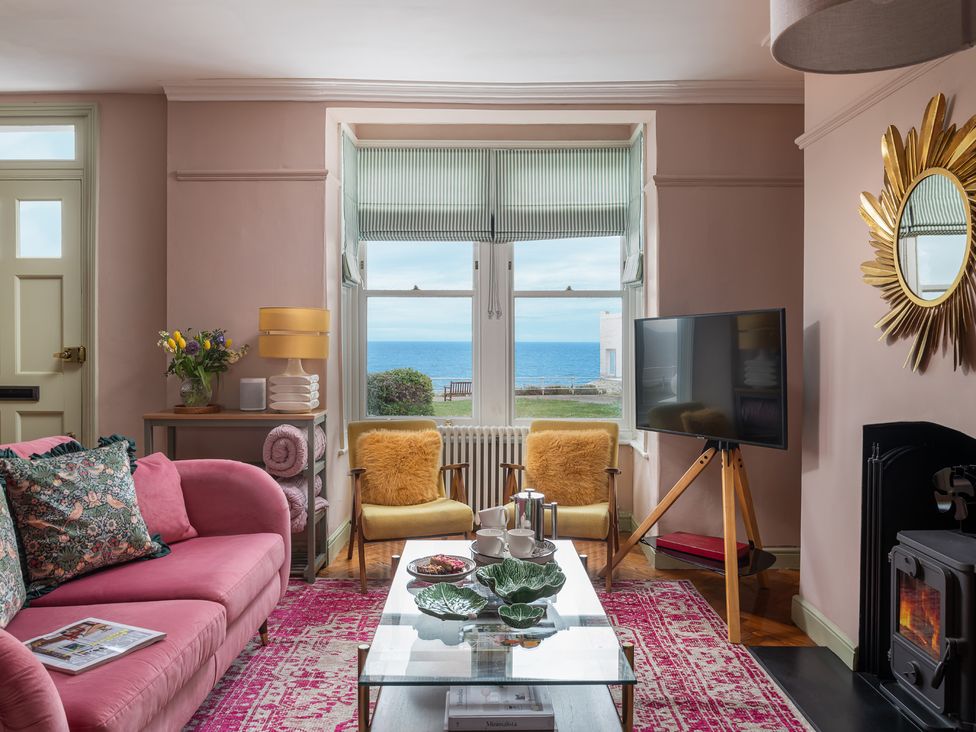 A living room with a sofa, TV and coffee table at Astondene, East Cliff, Southwold