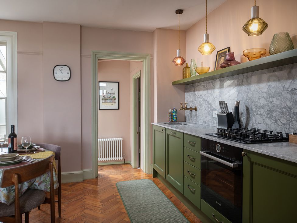 A kitchen with green cabinets and a dining table at Astondene, East Cliff in Southwold