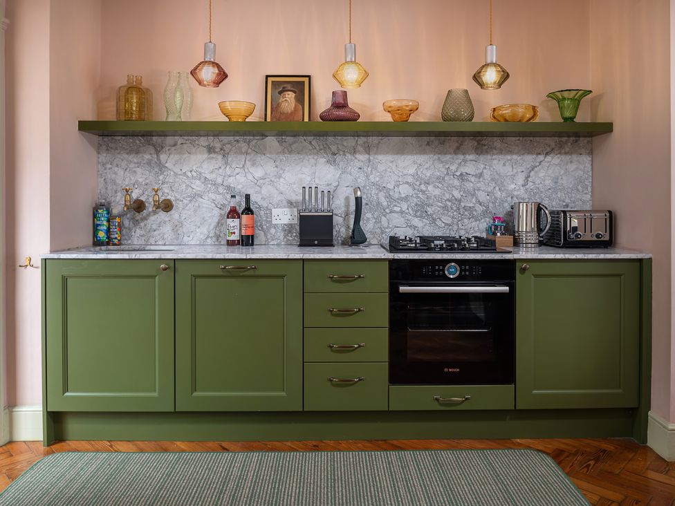 A kitchen with green cabinets and marble countertop at Astondene, East Cliff Southwold
