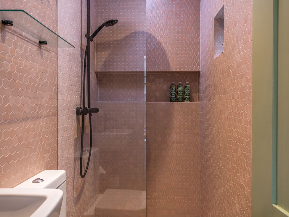 A shower with glass panel and shelving in a bathroom at Astondene, East Cliff, Southwold