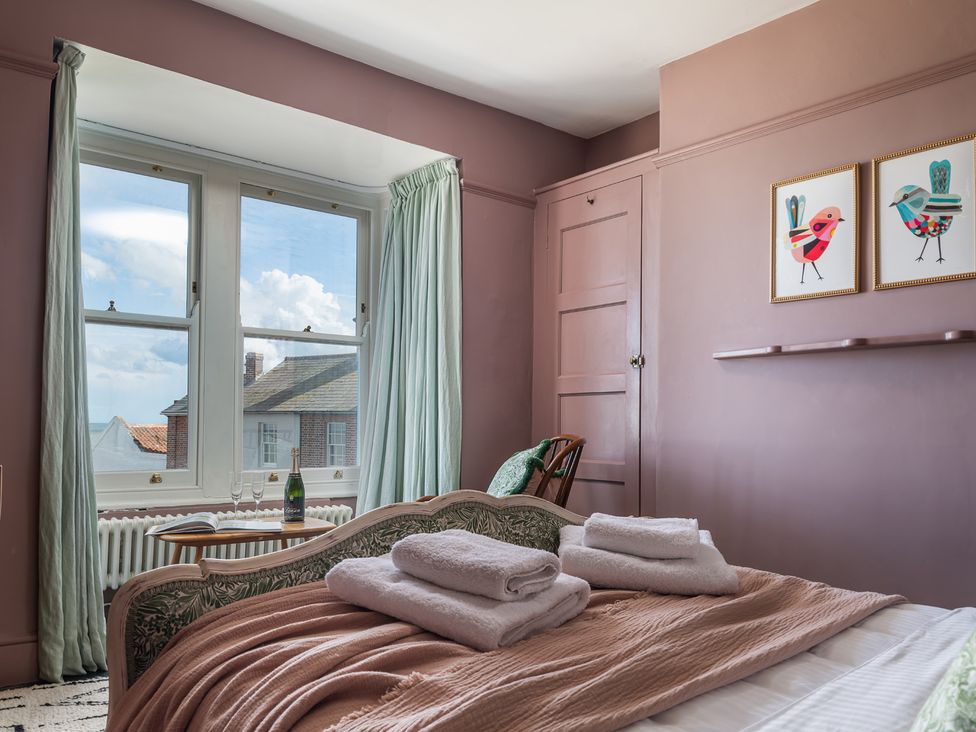 A bedroom with bed towels and windows at Astondene, East Cliff in Southwold