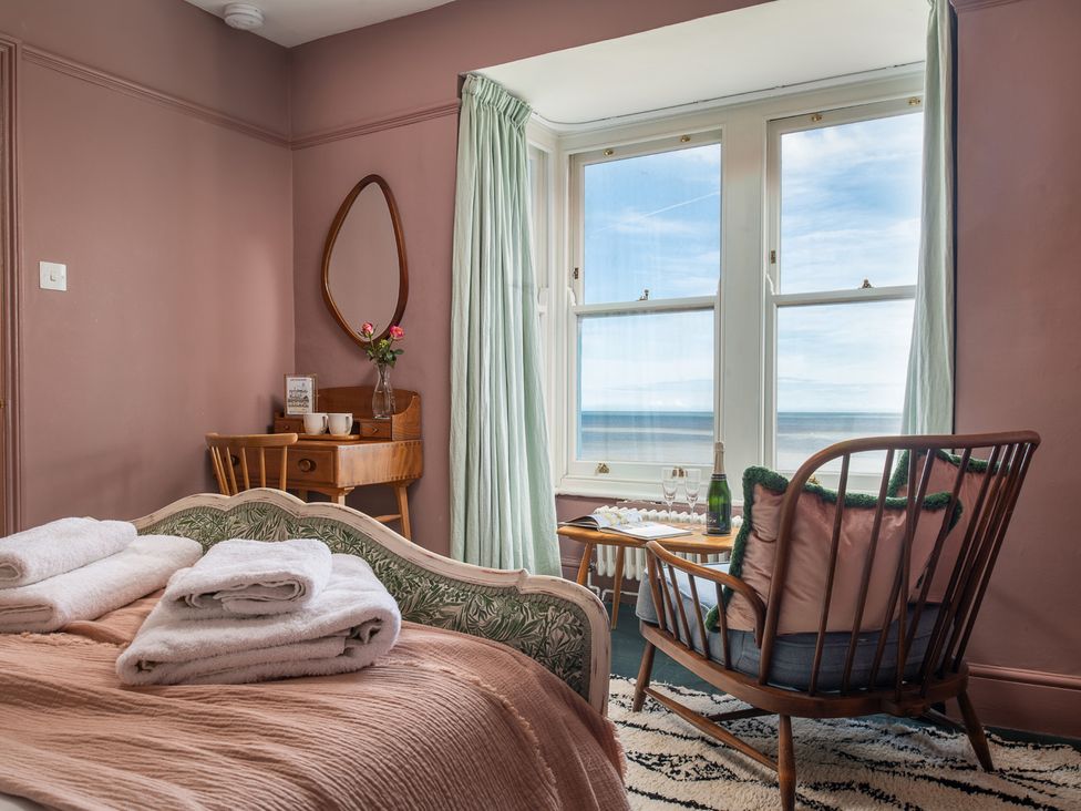 A bedroom with a view of the sea and a chair at Astondene, East Cliff Southwold