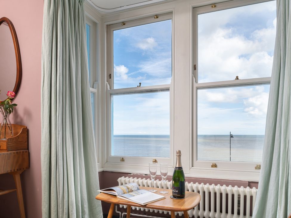 A window view with a table holding champagne and a magazine at Astondene, East Cliff Southwold
