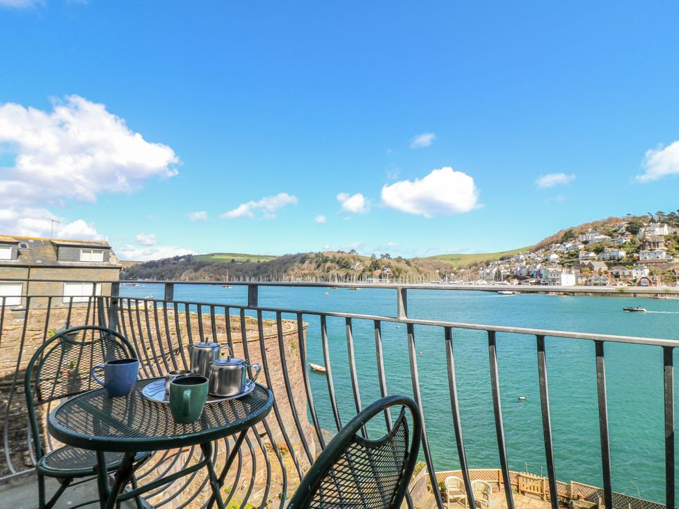 A balcony with a table and chairs overlooking a river at Harbourside Dartmouth