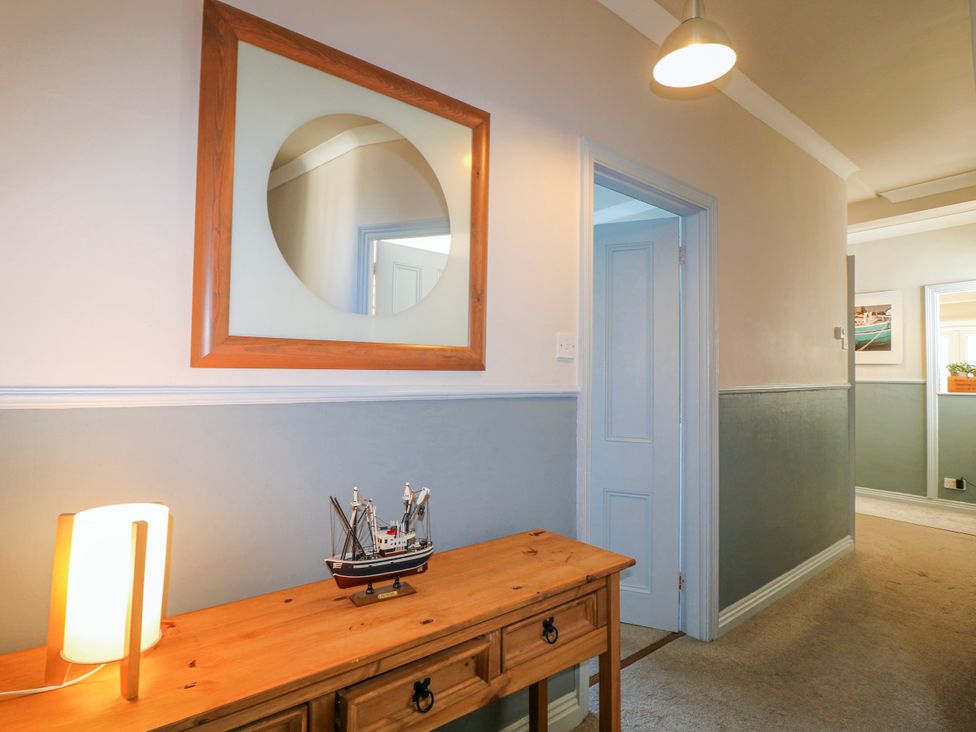 A hallway with a mirror and a model ship on a table at Harbourside in Dartmouth