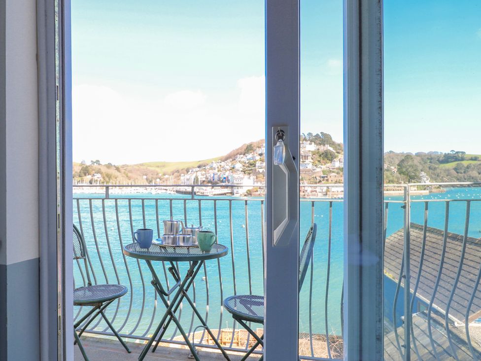 A balcony with a table and chairs overlooking a water view at Harbourside in Dartmouth