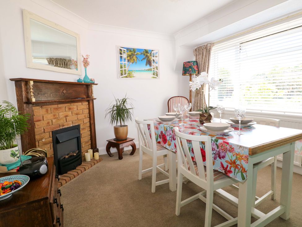 A dining room with a table set for four near a window and a brick fireplace at Lavender Cottage in Hailsham