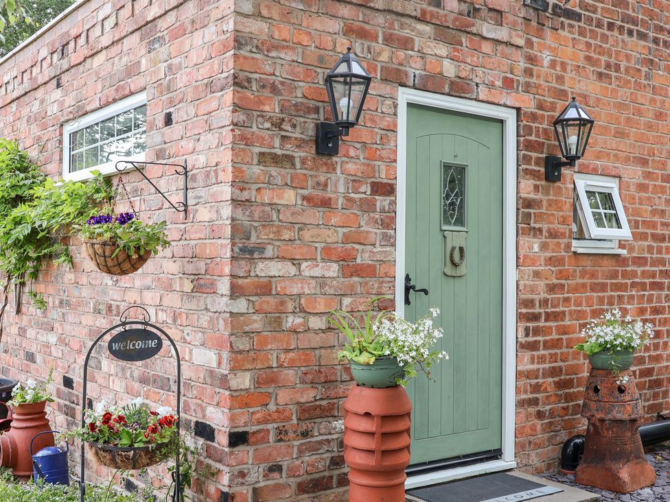 An entrance with a green door and flower pots at The Stables in Chester