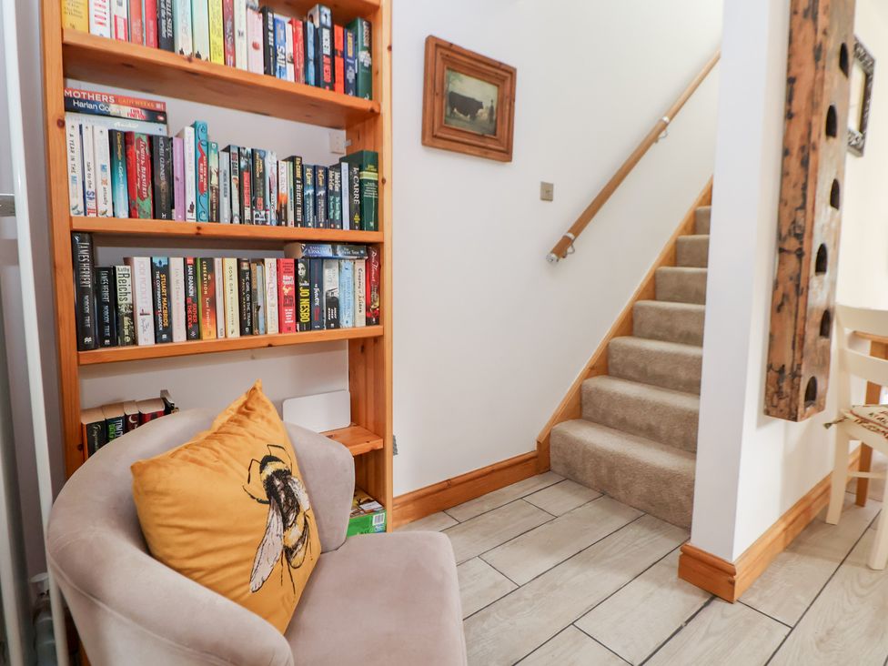 A hallway with a bookshelf, an armchair, and stairs at The Stables in Chester
