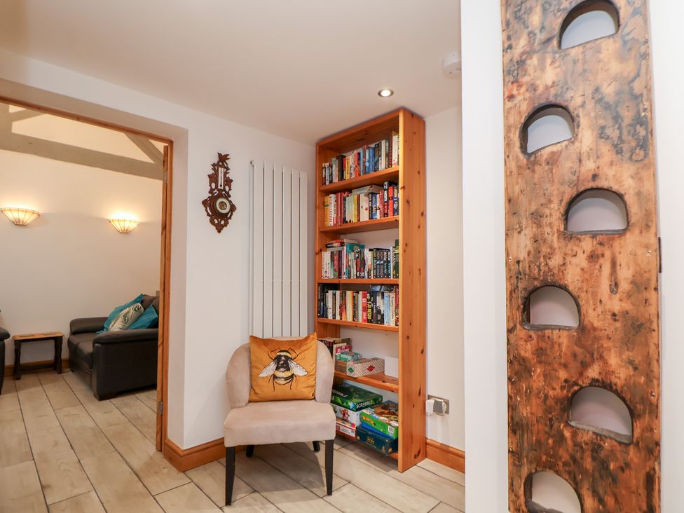 A sitting room with a bookshelf and an armchair at The Stables in Chester