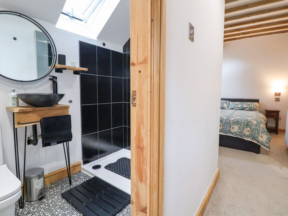 A bathroom with a shower and a bed visible at The Stables in Chester