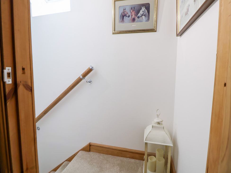 A staircase with a handrail and picture frames at The Stables in Chester