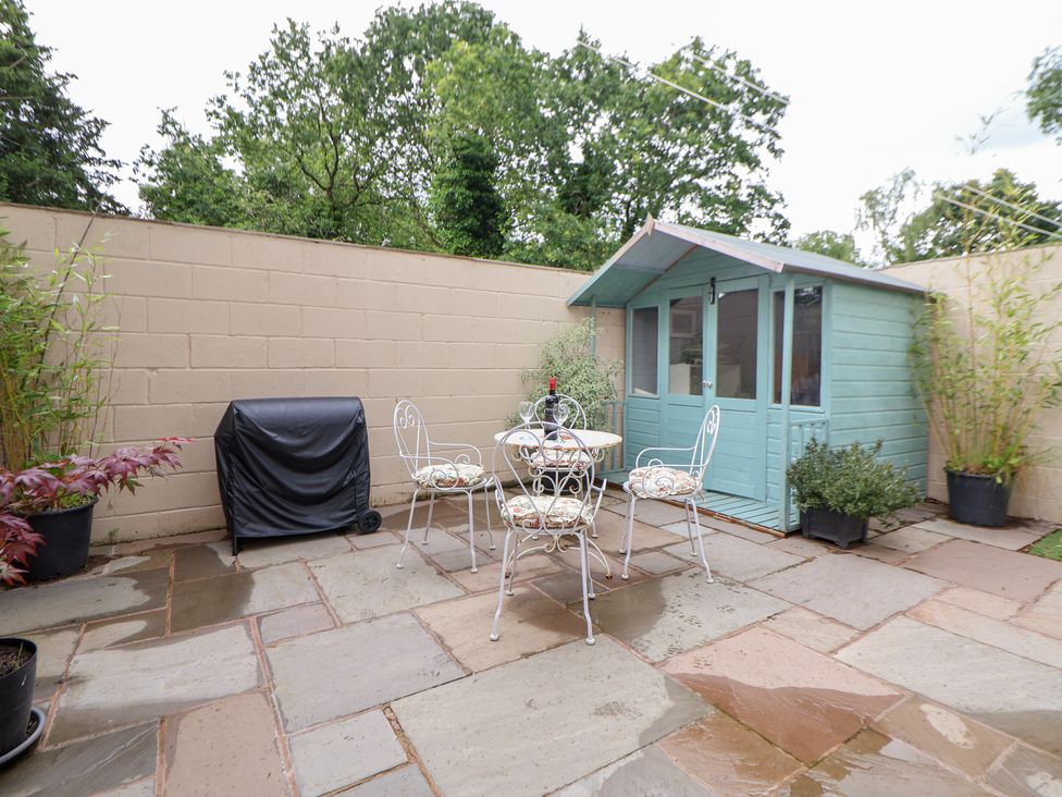 A garden with a table and chairs beside a shed at The Stables in Chester