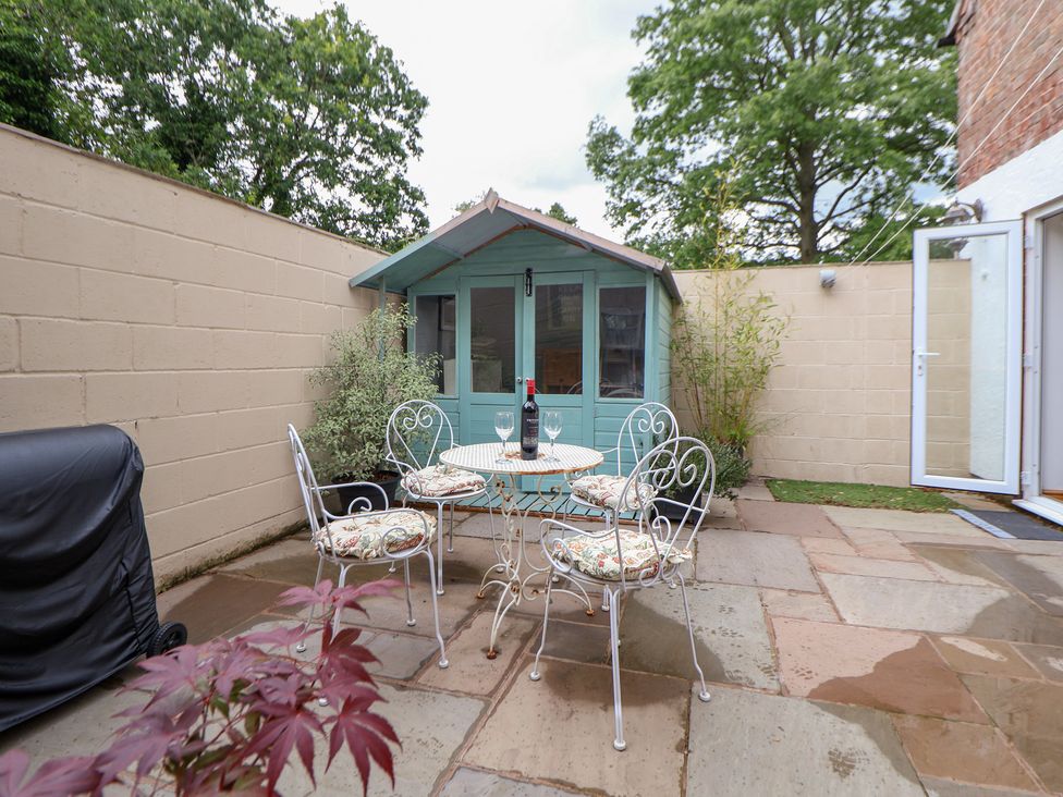 A garden with a patio, table, and chairs at The Stables in Chester