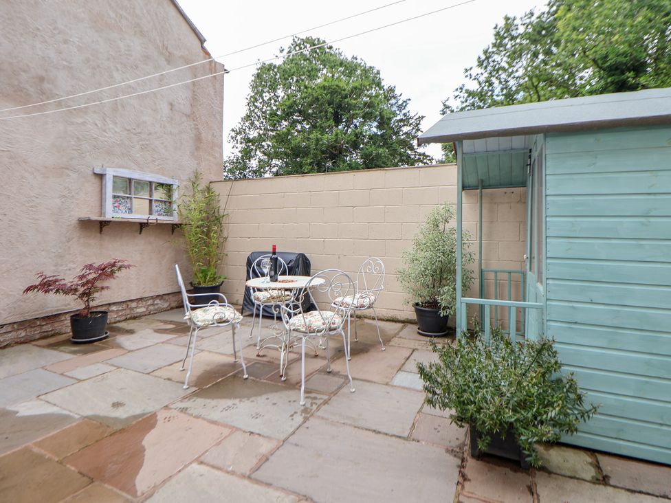A garden with a table and chairs, and a shed at The Stables in Chester
