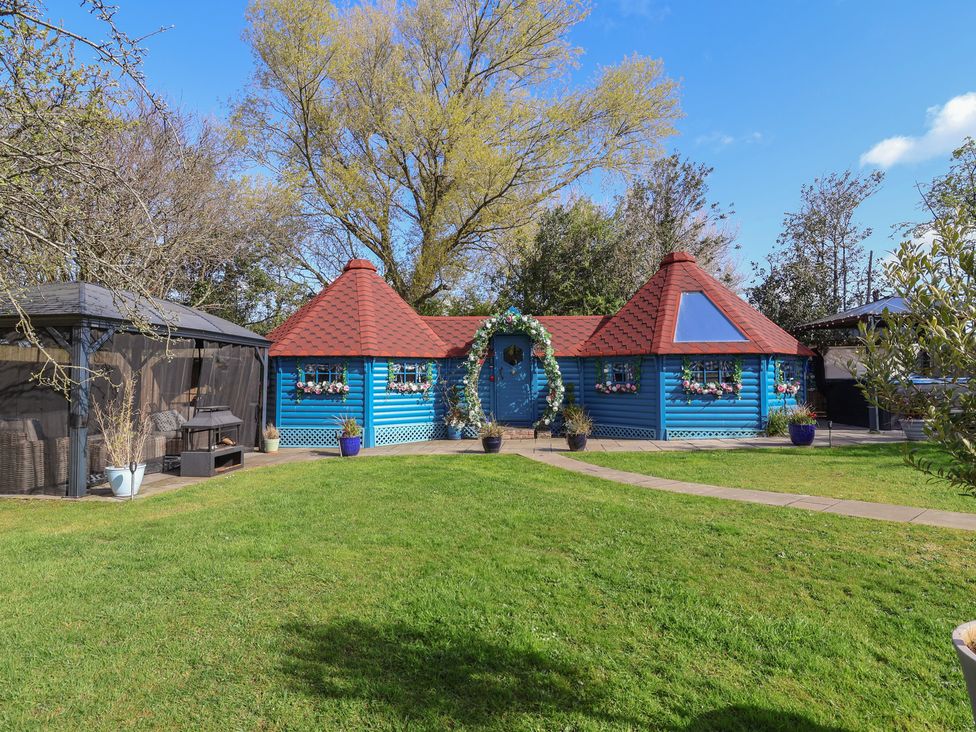 A blue cottage with a red roof and garden at Applejacks Orchard in Holywell