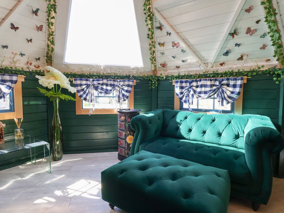 A sitting room with a green sofa and vase at Applejacks Orchard Holywell