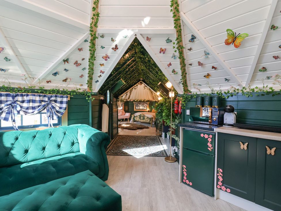 A living room with a sofa and kitchen area at Applejacks Orchard in Holywell
