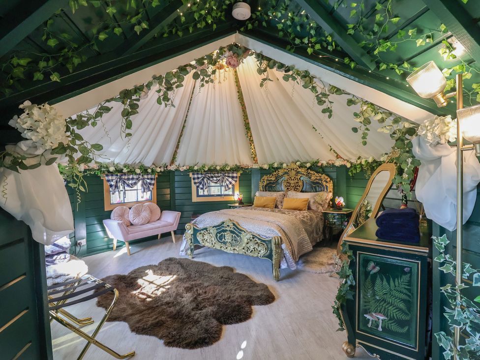 A bedroom with a bed, sofa, and dressing table at Applejacks Orchard in Holywell