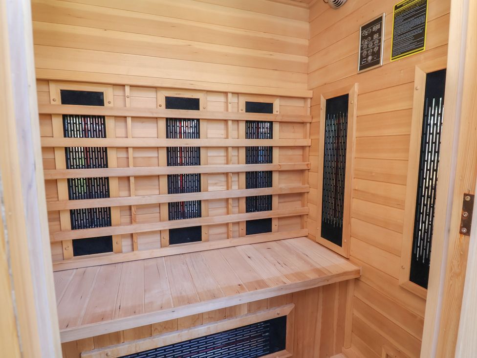 A sauna interior with seating bench and heat panels at Applejacks Orchard Holywell